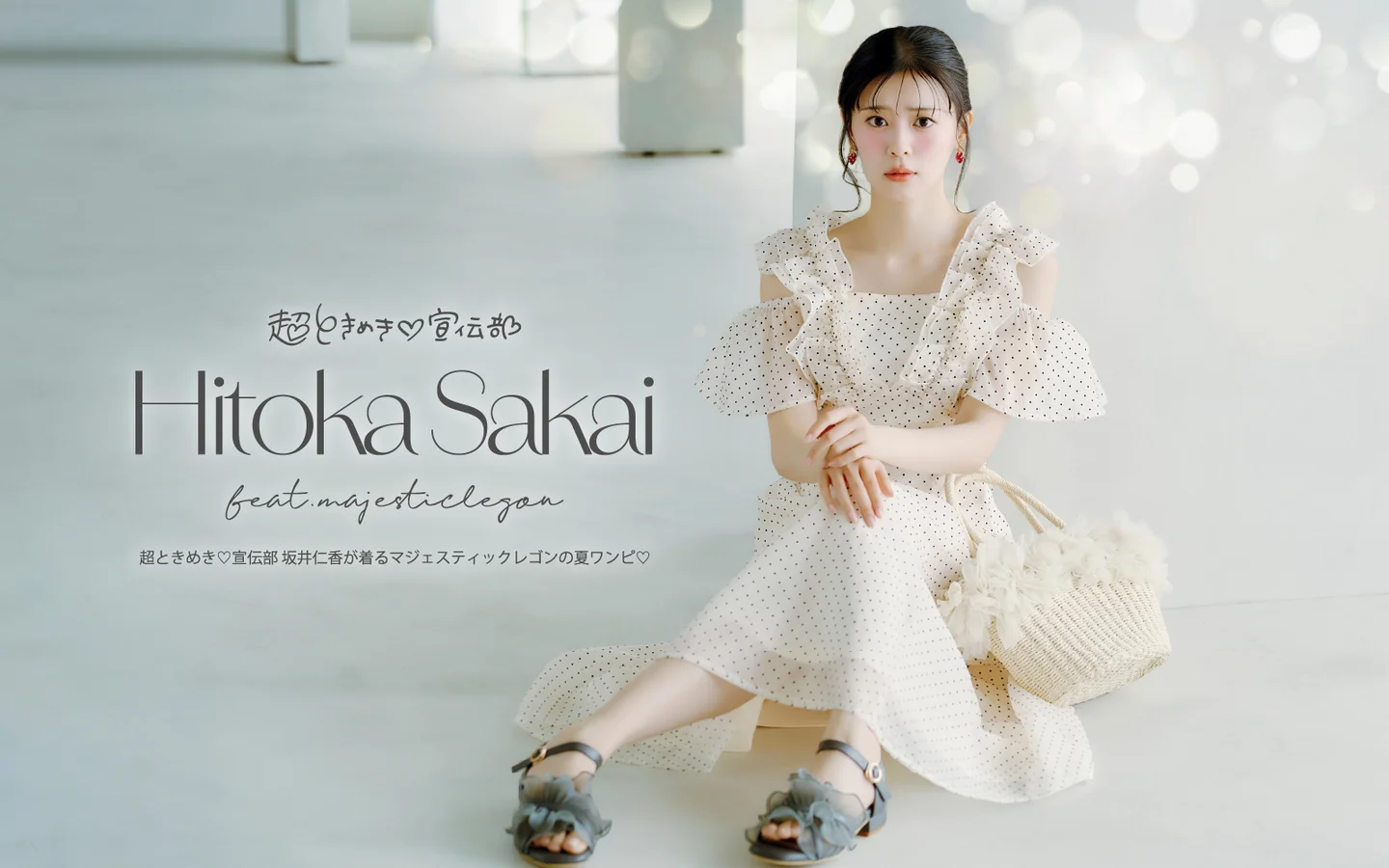 坂井仁香が水玉模様のフリルワンピースを身にまとい、白い背景の前でポーズを取るファッションショット