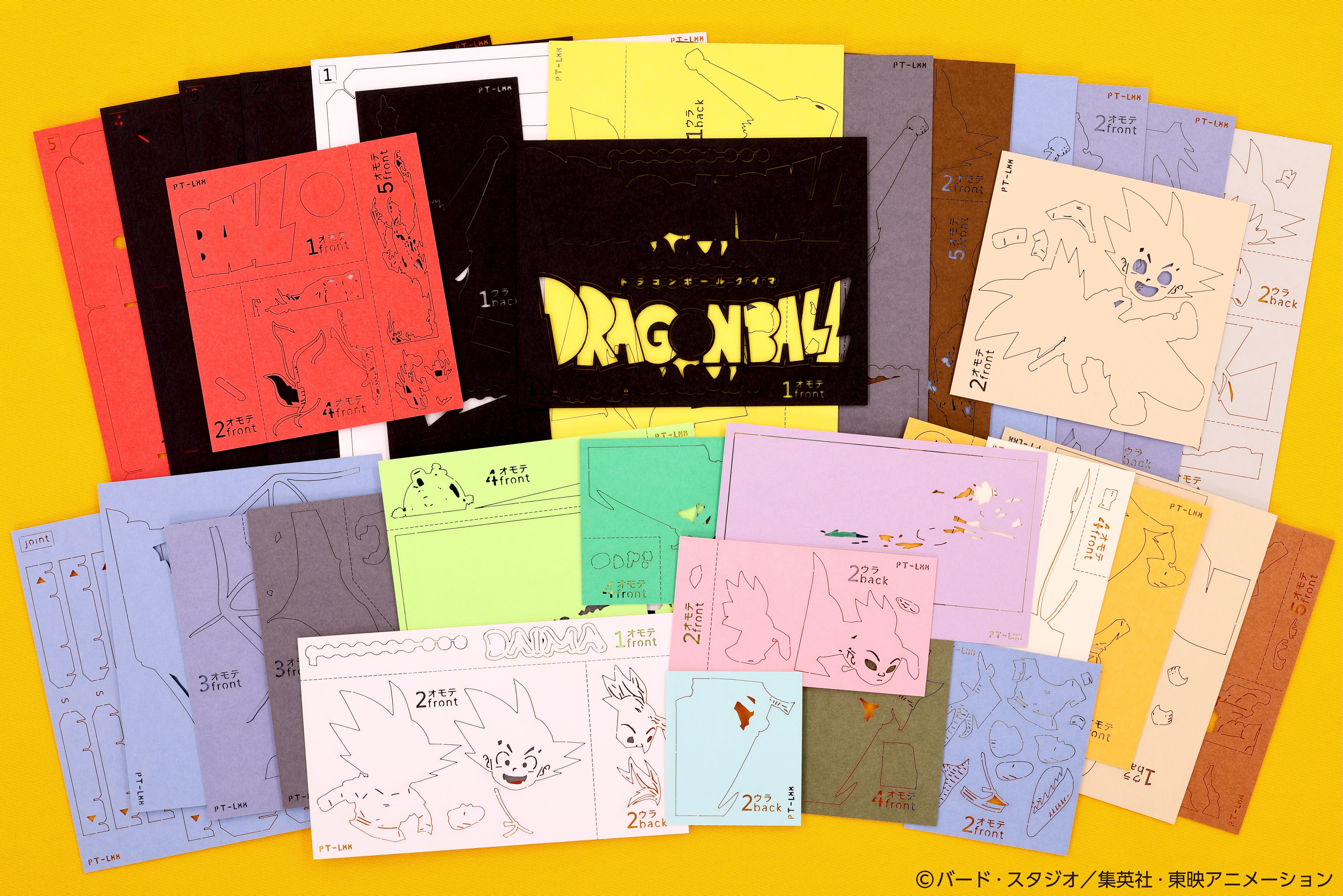 多色の紙で構成された『ドラゴンボールDAIMA』のペーパークラフトキットの各パーツが並べられている。
