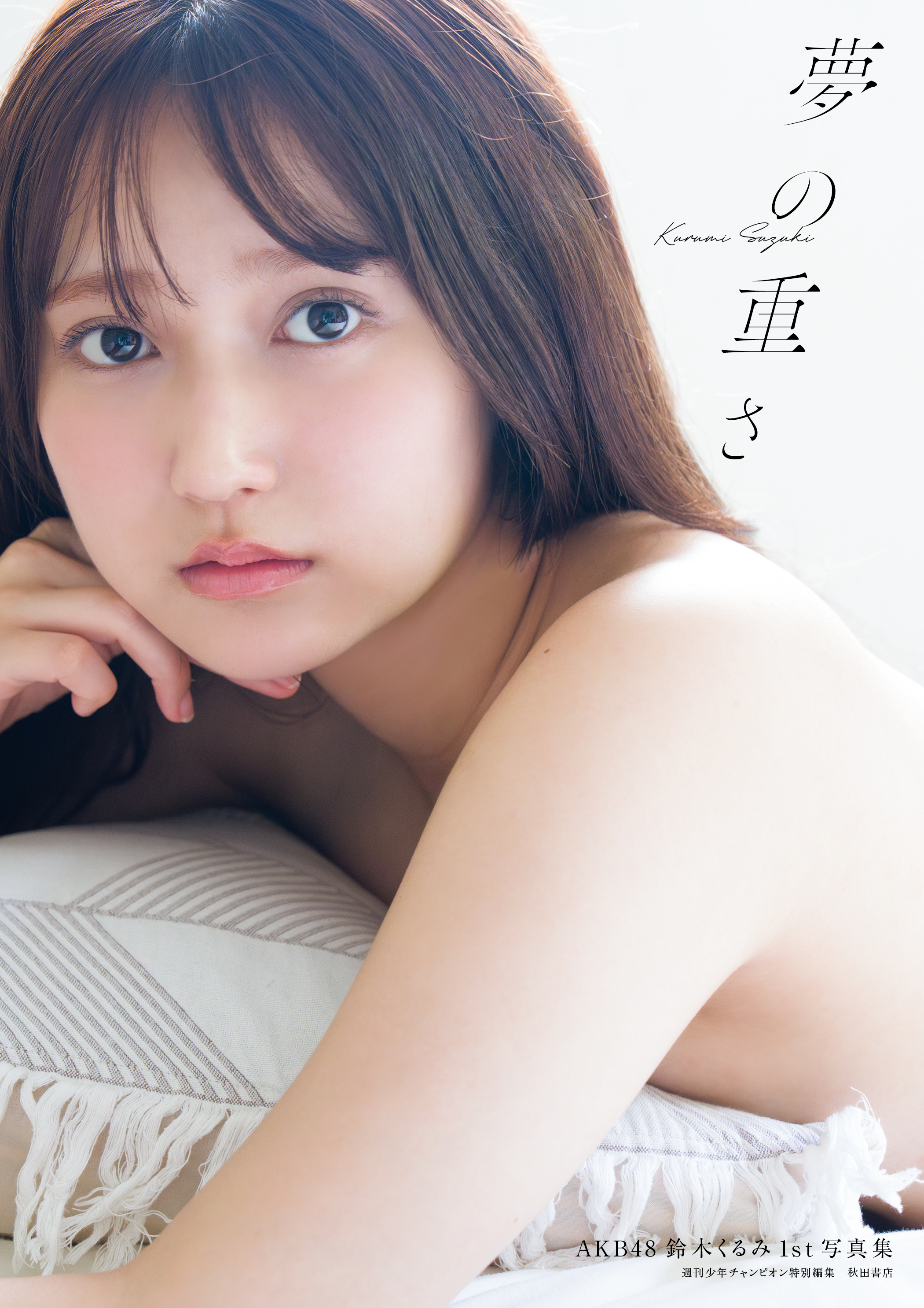AKB48の鈴木くるみの1st写真集『夢の重さ』の表紙画像。彼女が柔らかい表情を見せながら、片手で顎を支えている姿が印象的。背景は明るい光に包まれている。