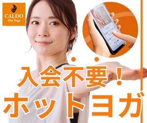 女性がホットヨガのアプリをスマートフォンで操作しながら笑顔でポーズをとっている様子。
