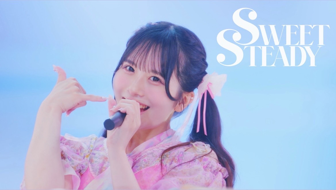 次世代アイドルグループSWEET STEADYのメンバーがマイクを持ち、明るい笑顔でポーズをとっています。背景は青色で、グループ名が上部に表示されています。