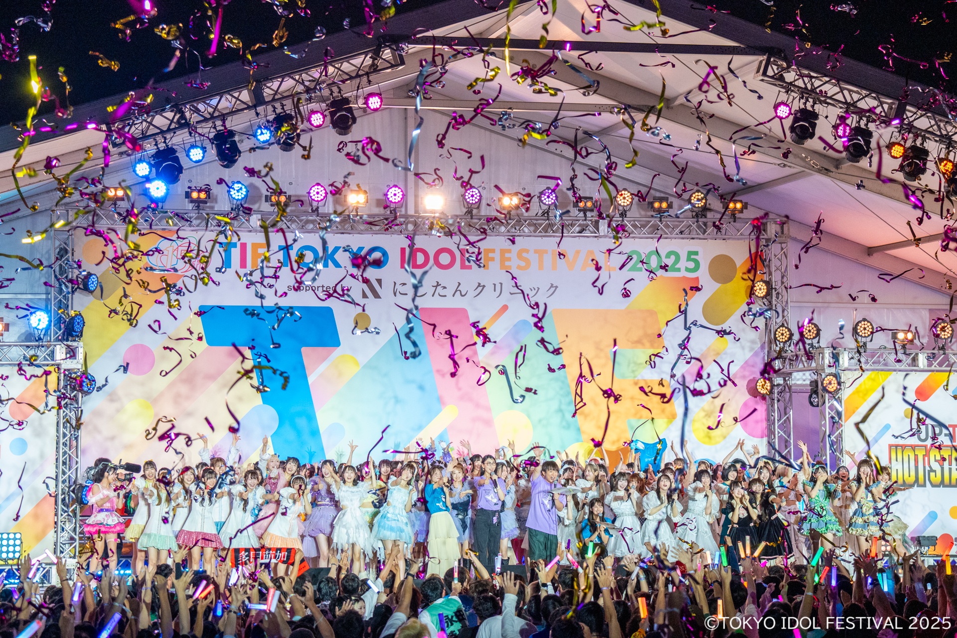 TOKYO IDOL FESTIVAL 2025のフィナーレで、アイドルたちが集まってパフォーマンスを行い、カラフルな紙吹雪が舞い上がるシーン