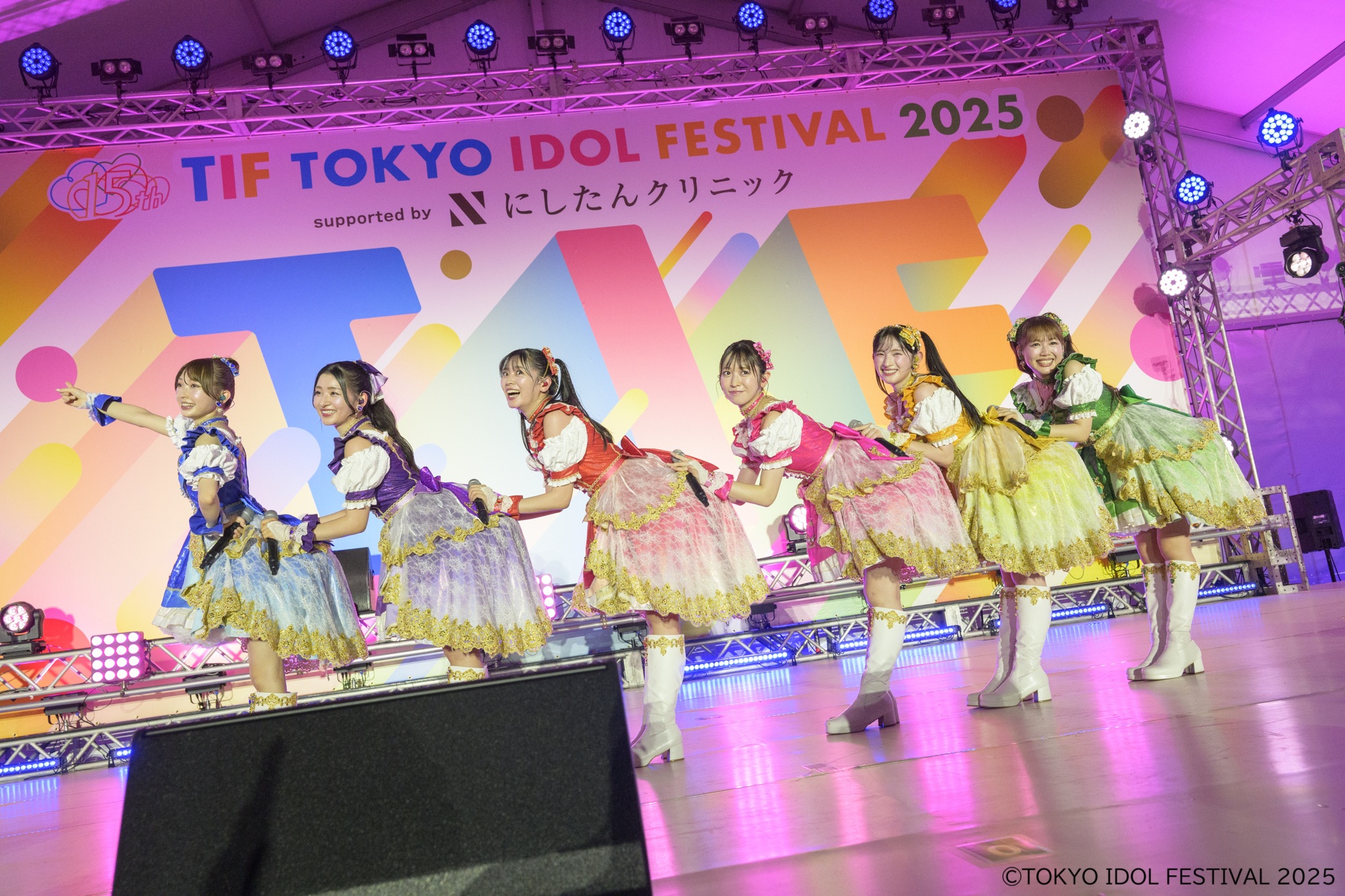 アイドルグループがカラフルな衣装を着てステージ上でパフォーマンスしている様子。背景には「TIF TOKYO IDOL FESTIVAL 2025」のロゴが見える。
