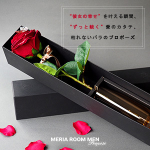 赤いバラと宝石の指輪が入った黒いプロポーズボックス。プロポーズのメッセージが書かれた背景と散らばったバラの花びらがあるシーン。