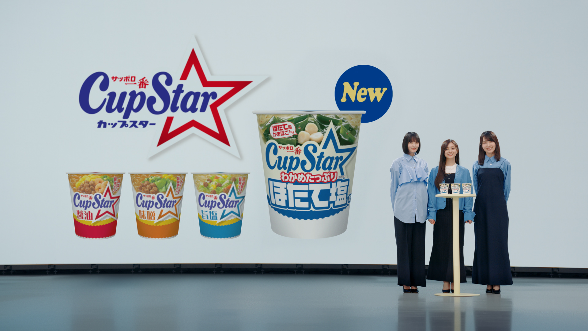 乃木坂46のメンバーが新しいカップスターのほたて塩味を紹介しているTVCMのシーン。彼女たちが青い衣装を着て、カップスターポットの前で笑顔を向けている。