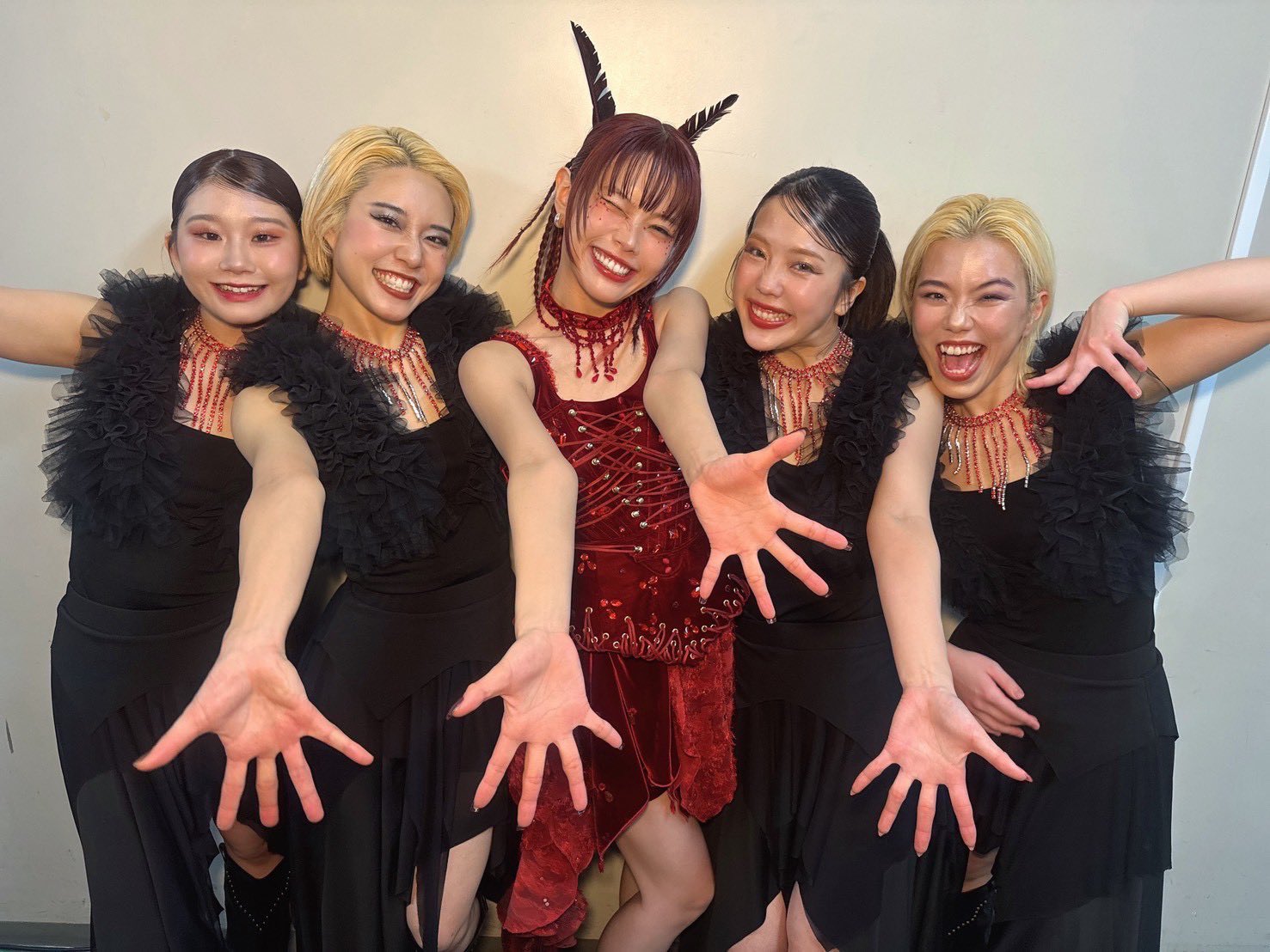 アイナ・ジ・エンドと4人のダンサーが笑顔でポーズをとる backstage の写真。アイナは赤い衣装を着ていて、ダンサーは黒い衣装を着用している。